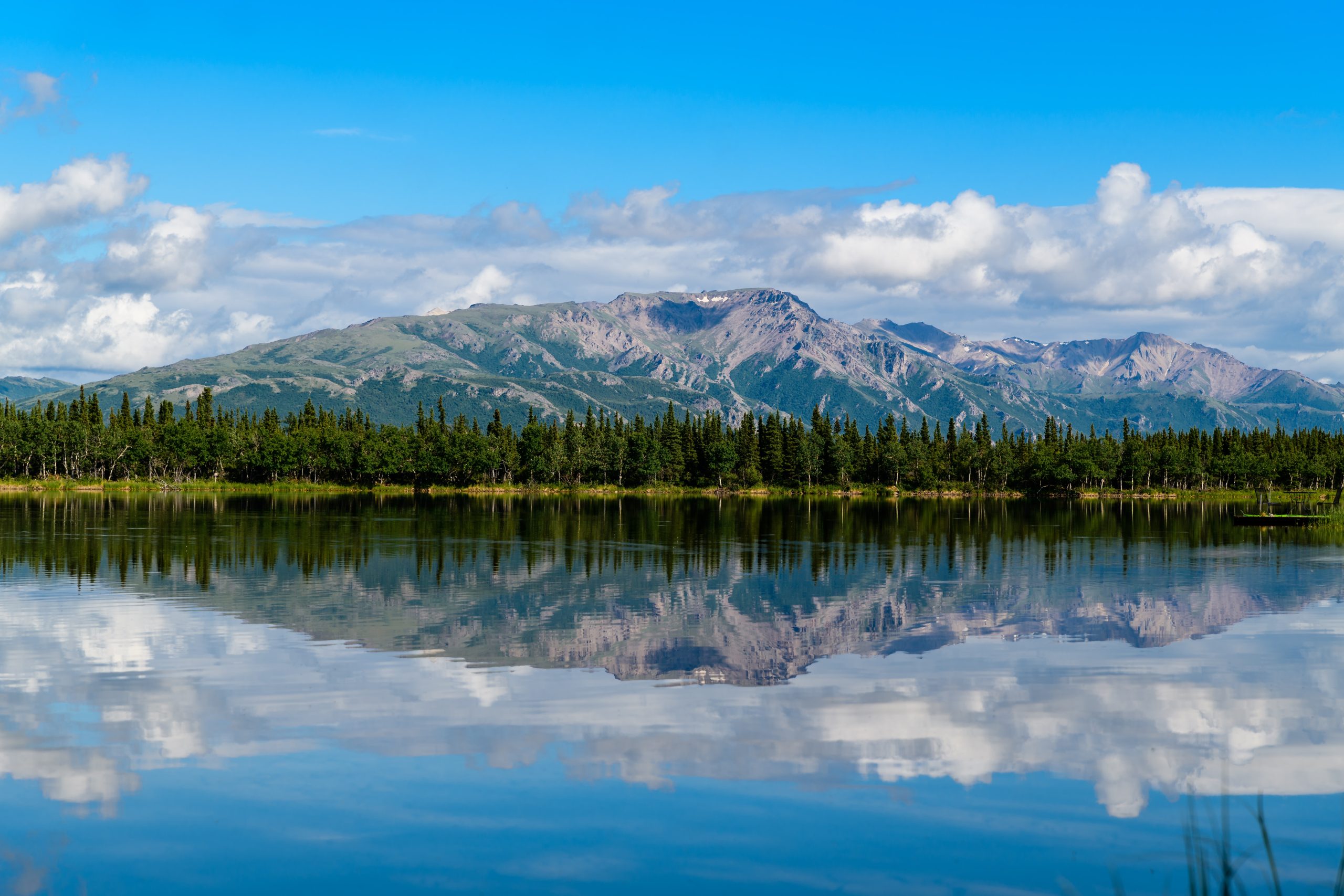 mountain and blue body of water under cloudy sky